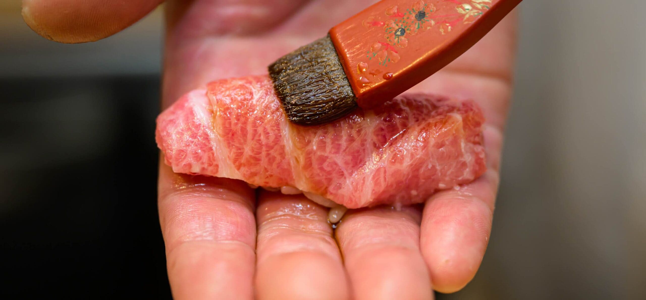 本鮪の握り寿司に刷毛で煮切り醤油を塗る職人の手元