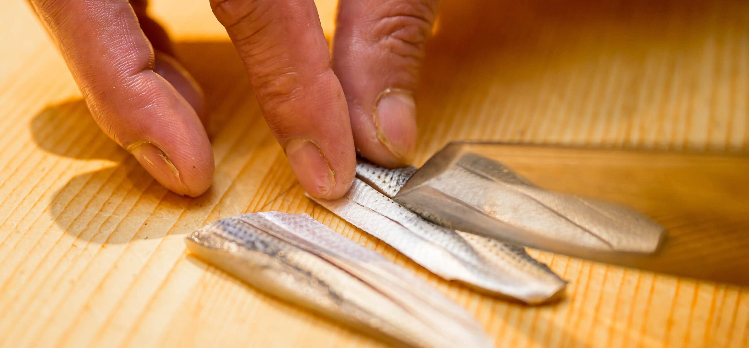 光り物の魚に丁寧に包丁を入れる仕込みの様子