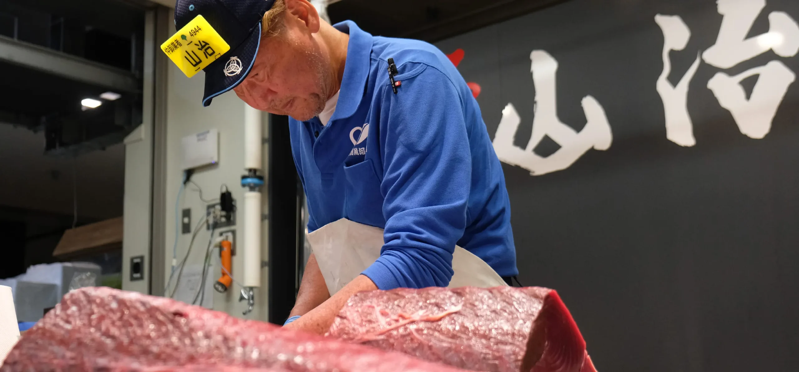 豊洲市場の鮪仲卸の男性が、大きな本鮪のブロックを切り分ける様子